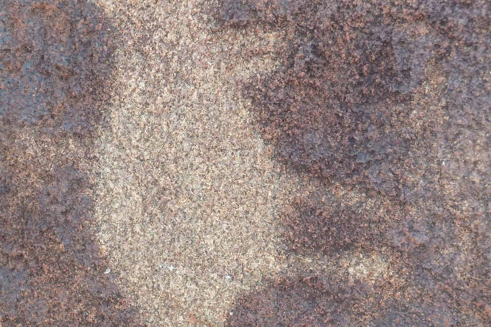 A pale engraved motif cuts across the dark patina of a boulder on the Burrup Peninsula.