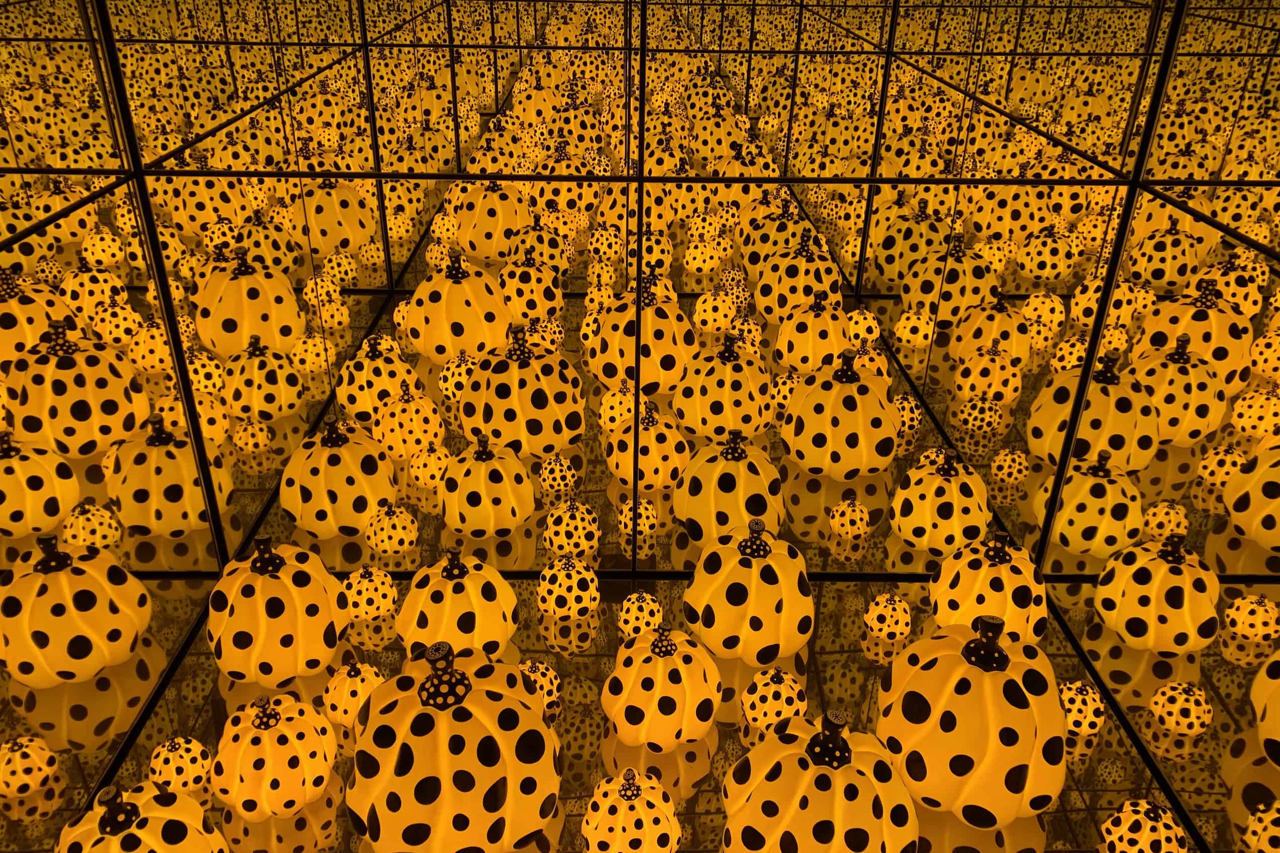 A yellow room covered in black dots surrounds a mirrored chamber filled with repeating pumpkin forms.