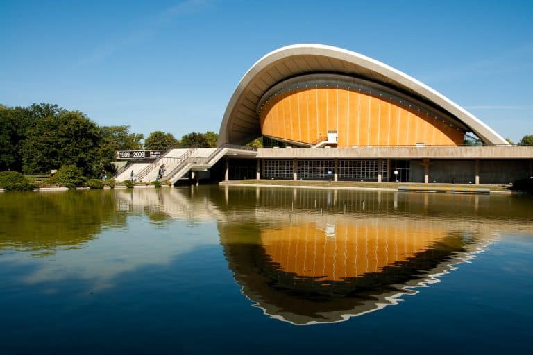 Haus der Kulturen der Welt and its reflecting pool beneath a blue sky in Berlin.
