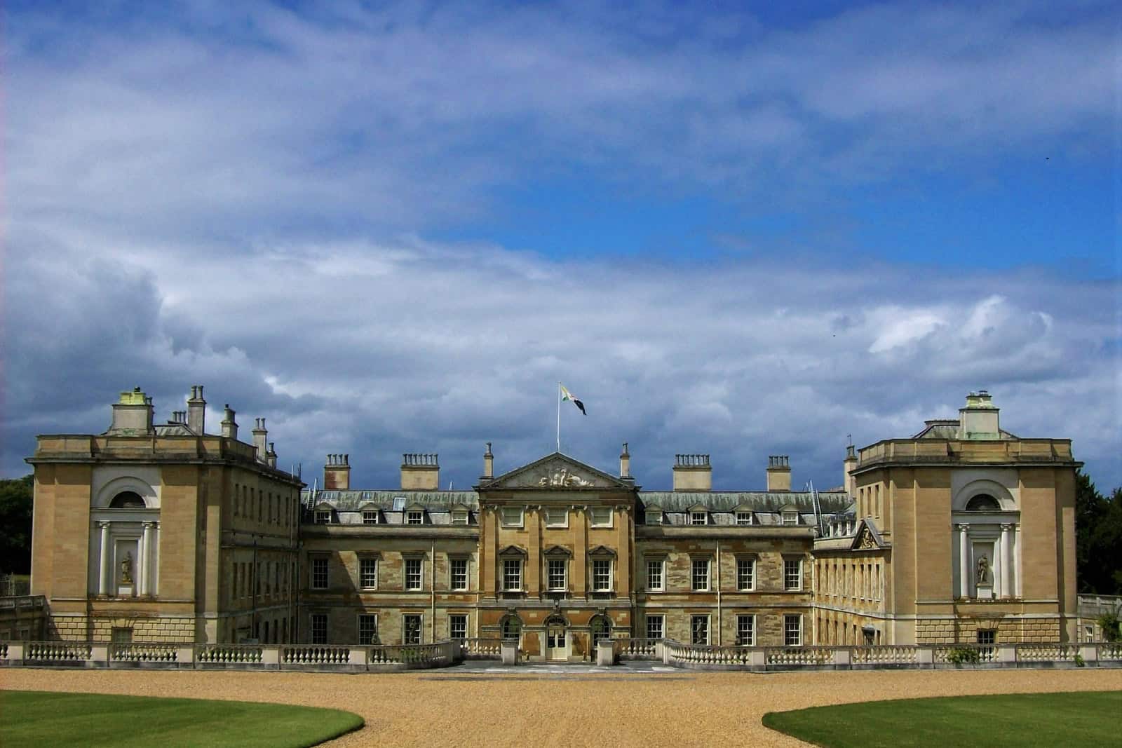 The neoclassical east front of Woburn Abbey seen across a broad lawn.