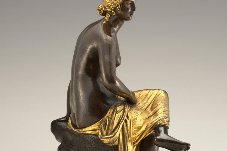 Antico’s Washington Seated Nymph cast shows a dark bronze woman with gilded hair and drapery seated on a round plinth.