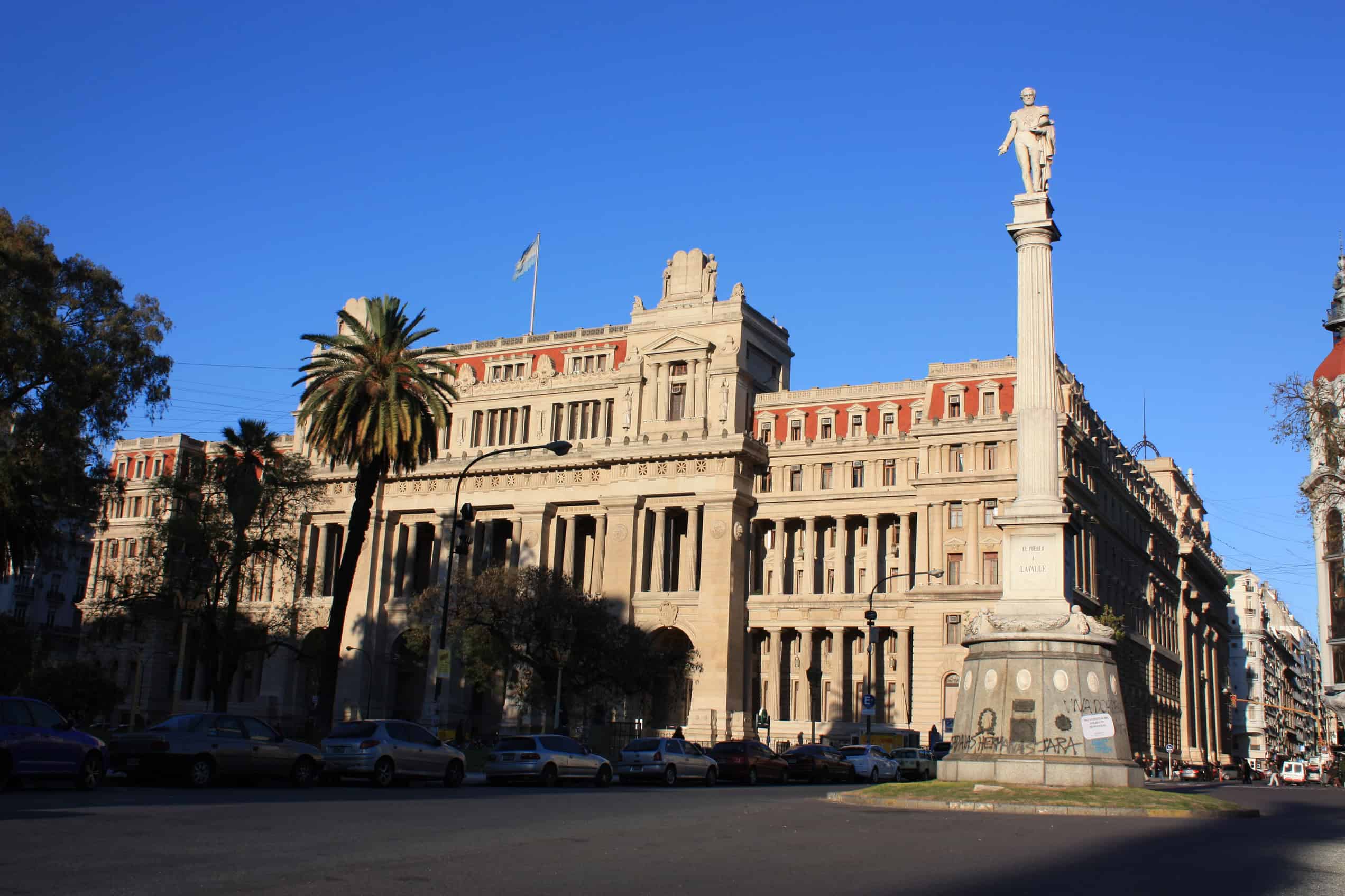 The Palace of Justice of the Argentine Nation stands behind trees and the Juan Lavalle monument in Buenos Aires.