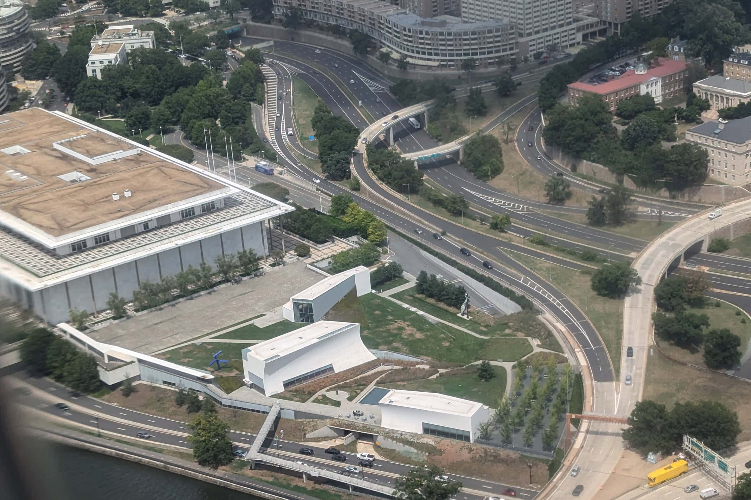 An aerial view shows the white pavilions and landscaped lawns of the REACH beside the Kennedy Center and Potomac River.