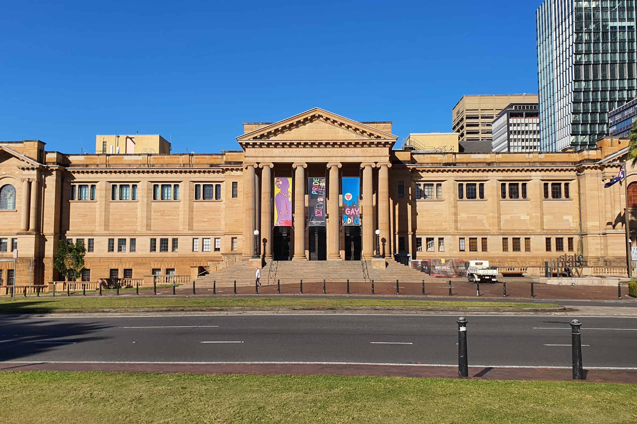 The sandstone facade and columned entrance of the State Library of New South Wales stand beneath a blue Sydney sky.