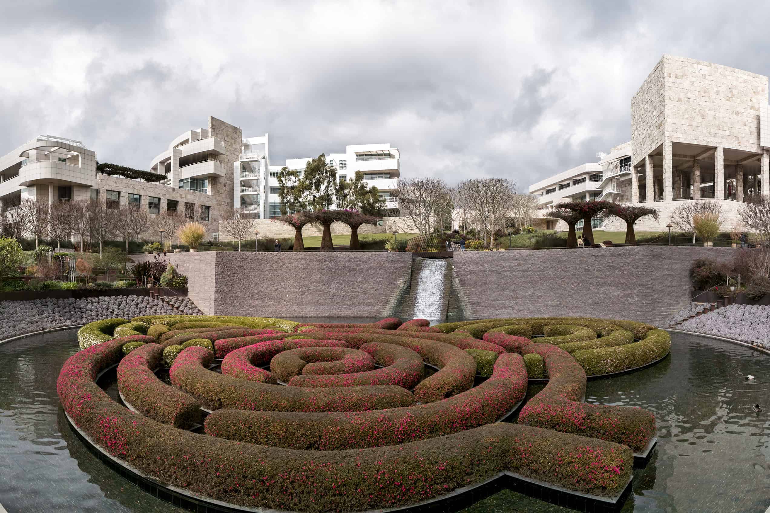 The Getty Center’s pale stone buildings rise behind green lawns and trees in the Central Garden.