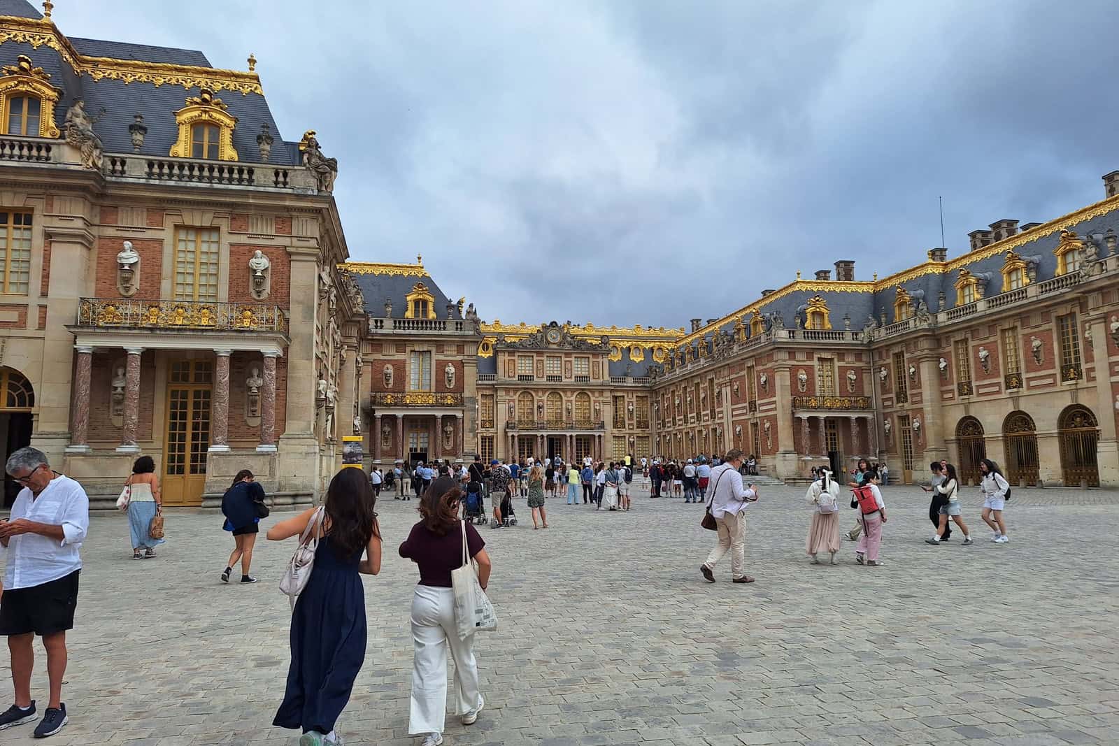 Exterior façade and forecourt of the Palace of Versailles in daylight.