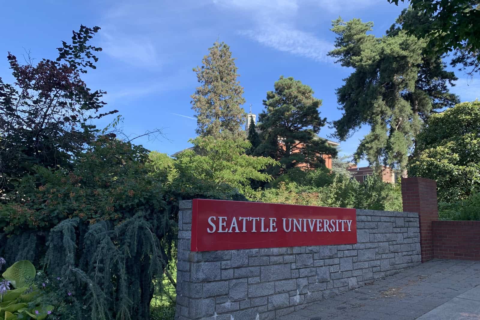 A Seattle University sign stands beside a landscaped campus entrance.