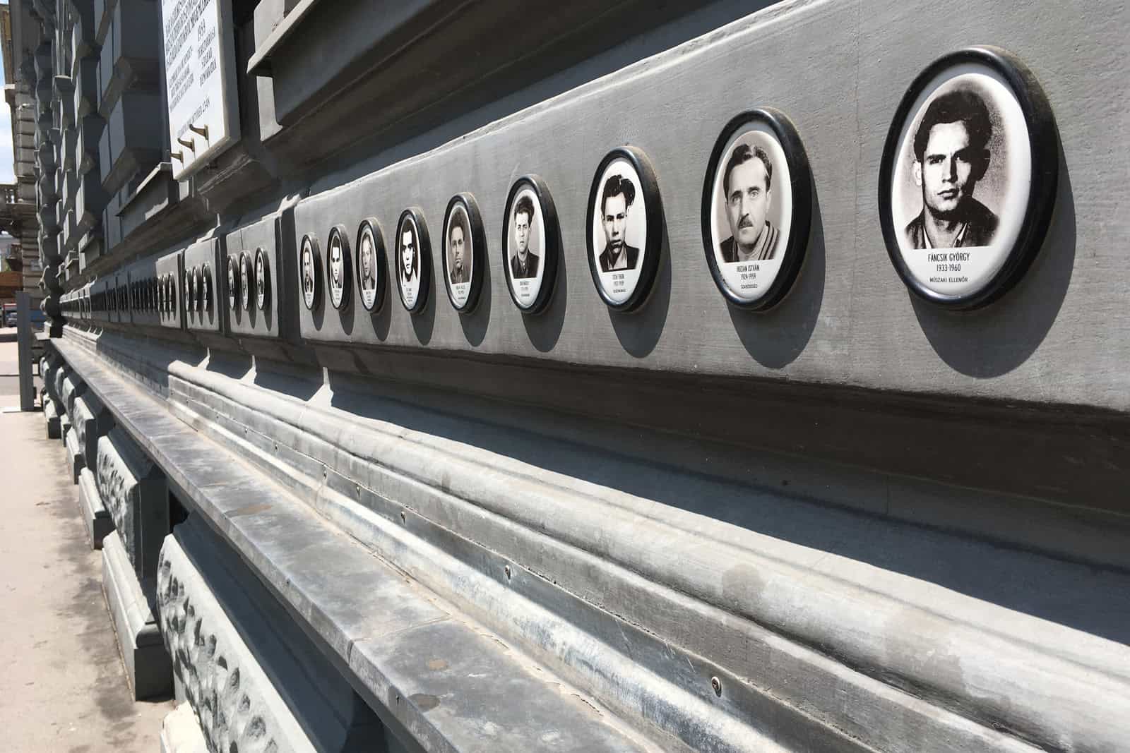 Rows of black-and-white victims’ portraits cover an exterior wall of Budapest’s House of Terror Museum.