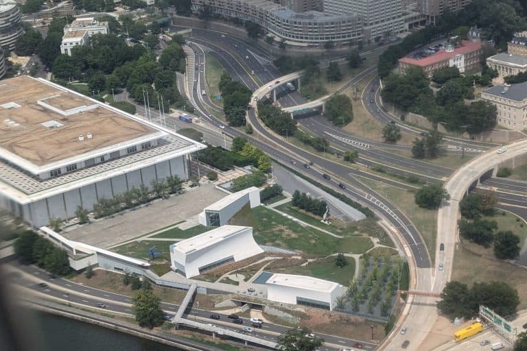 An aerial view shows the white pavilions and landscaped lawns of the REACH beside the Kennedy Center and Potomac River.