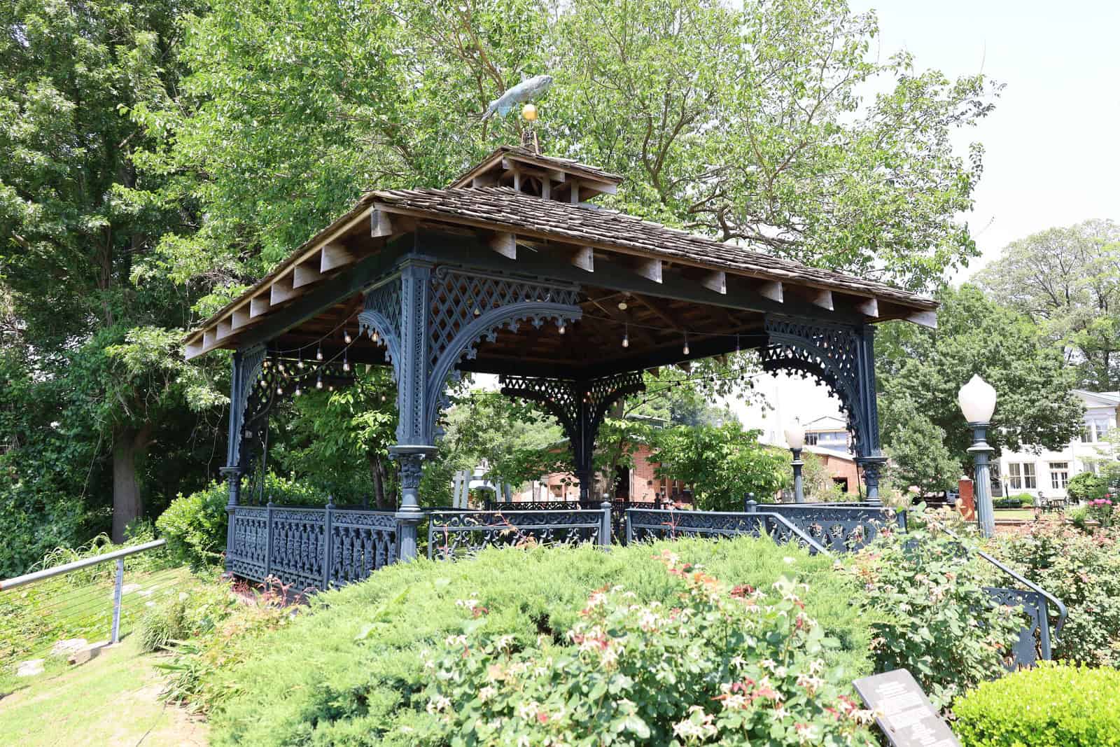 A white metal gazebo stands among the landscaped grounds of the Metal Museum’s Bluff campus.