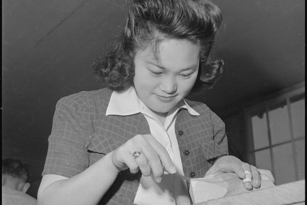 A young Japanese American resident works on a piece of birch in a wood-carving class at the Rohwer incarceration center in 1943.