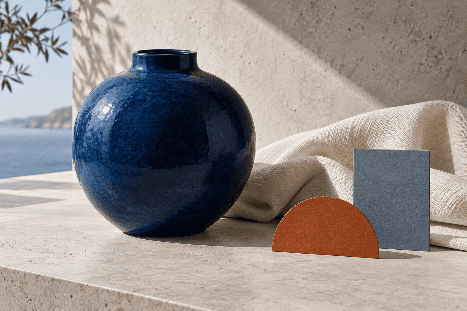 Deep blue ceramic vessel with ivory fabric, orange accent shape, and blue-gray card