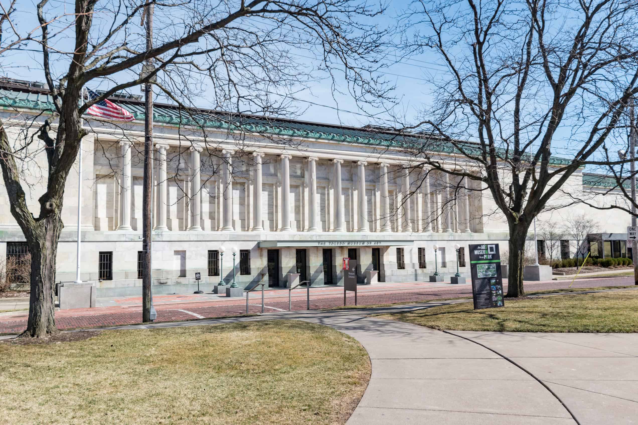 The neoclassical Toledo Museum of Art building seen across its lawn in daylight.