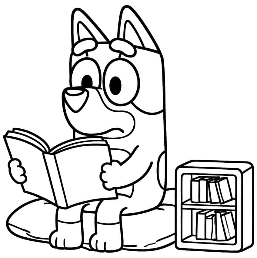 Pup sitting on a cushion reading an open book beside a small bookcase with books