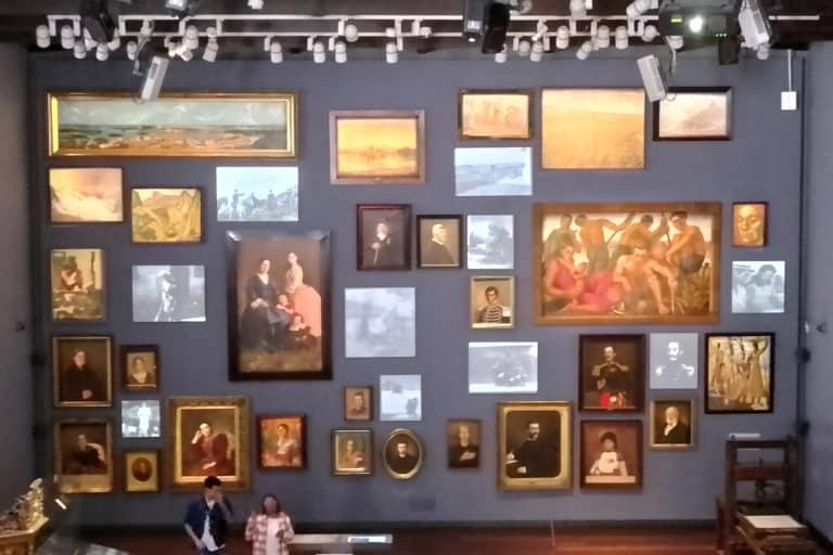 A wall of framed portraits, paintings and projected faces inside the Museo Nacional de Colombia’s Memoria y Nación gallery.