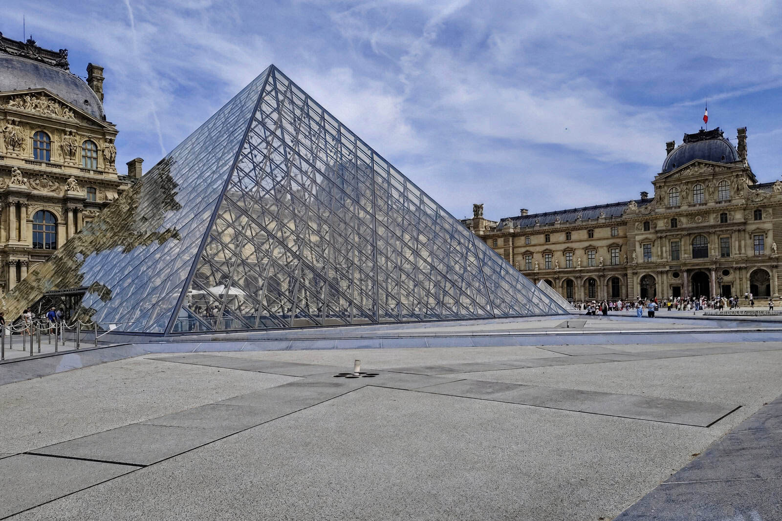 The glass Louvre Pyramid rises from the Cour Napoléon between the museum’s historic palace façades.