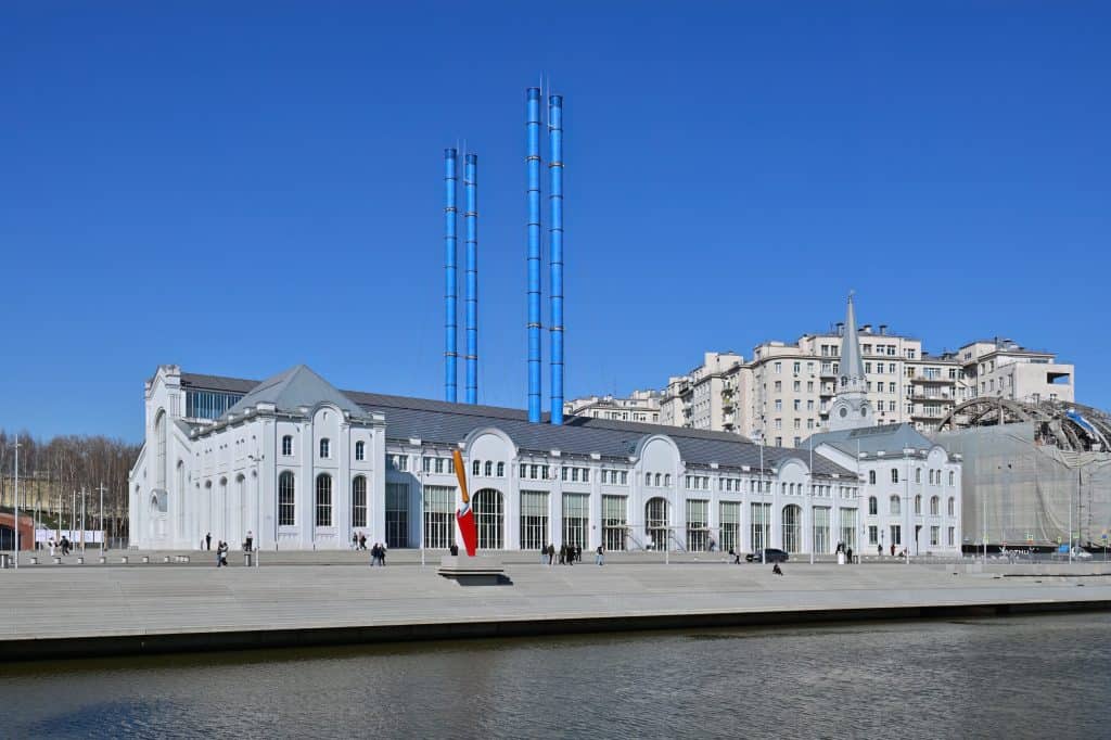 The white GES-2 House of Culture stands on Moscow’s embankment beneath four tall blue stacks.