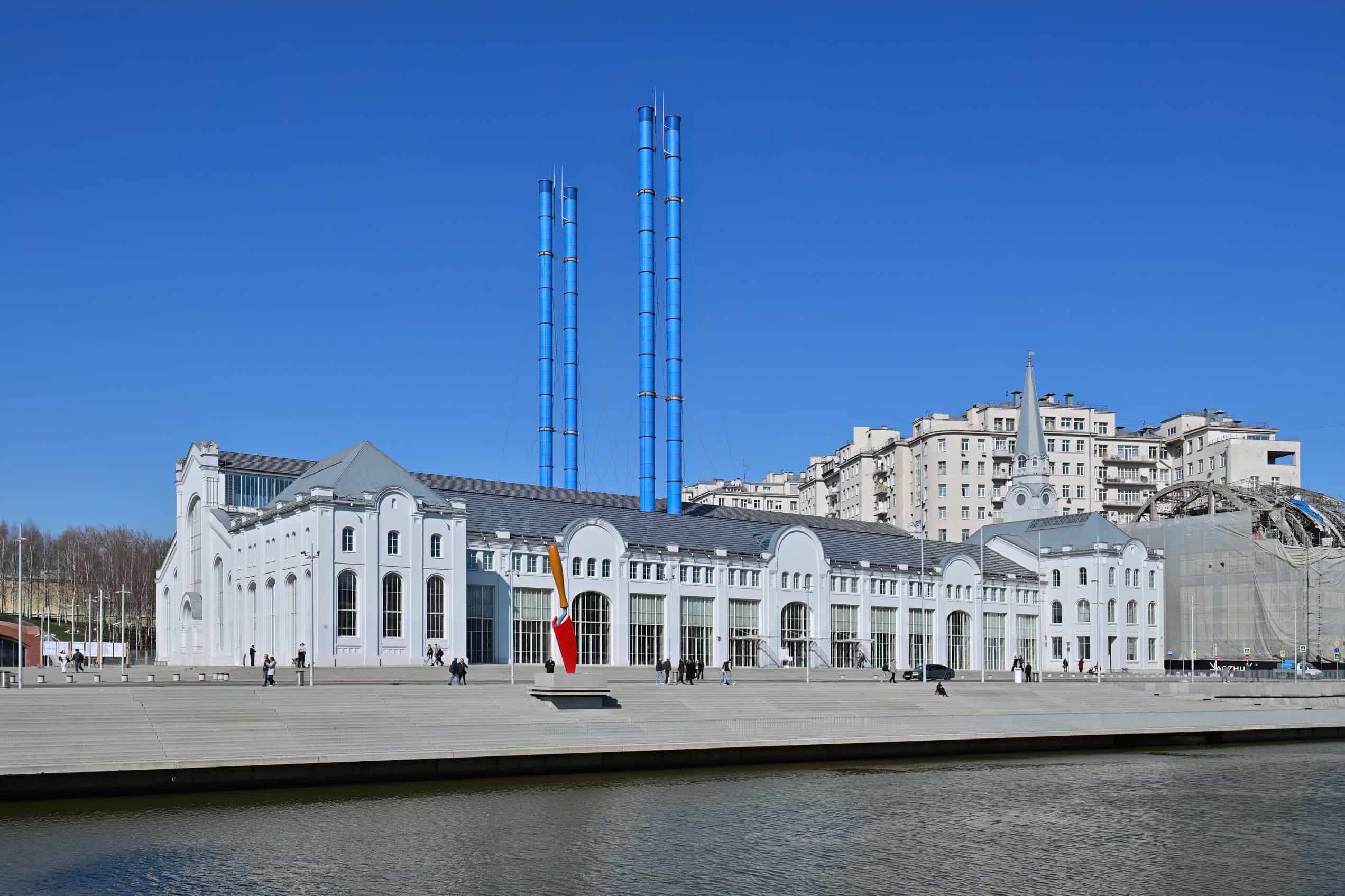 The white GES-2 House of Culture stands on Moscow’s embankment beneath four tall blue stacks.