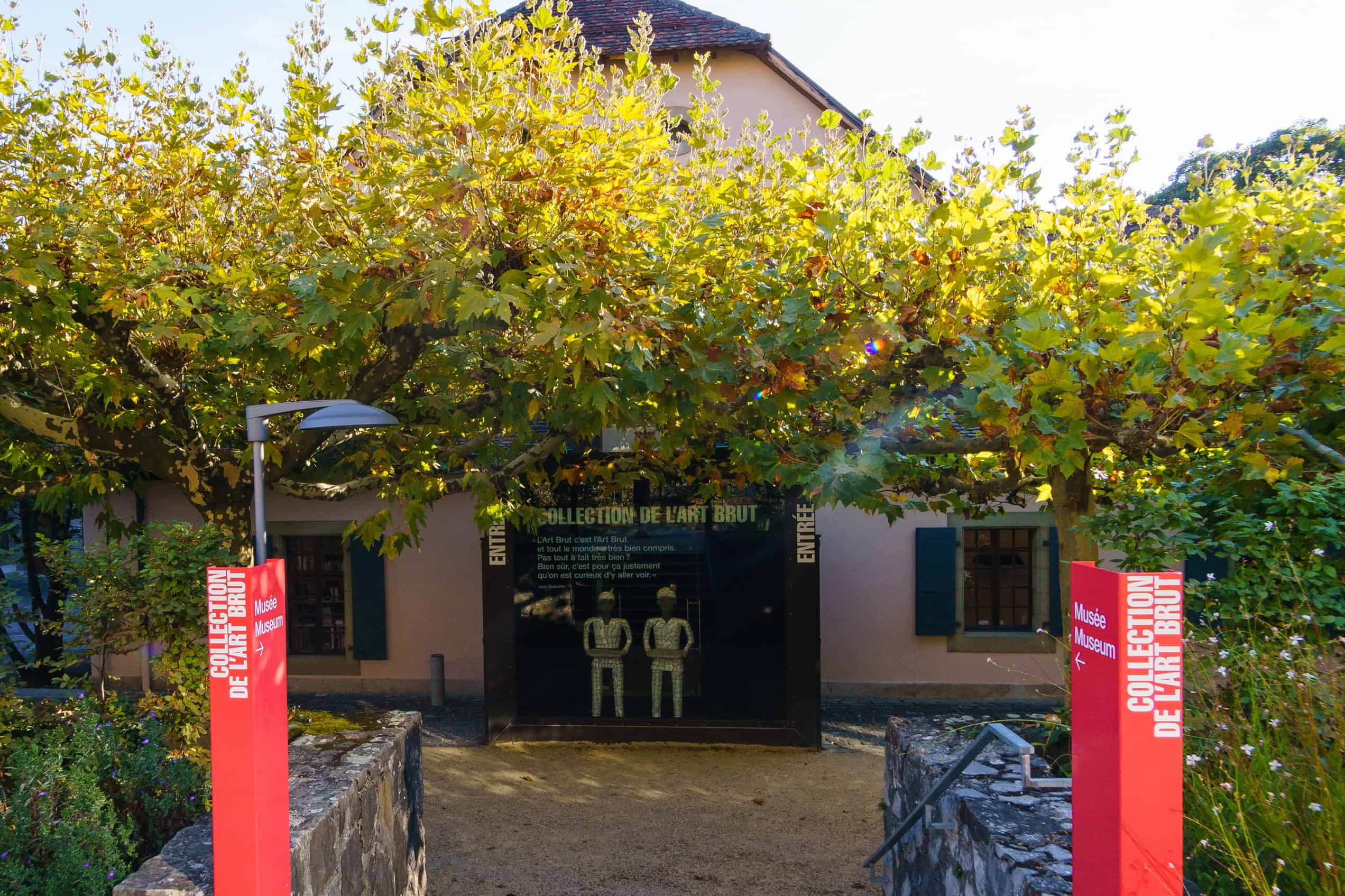 The pale stone exterior and tiled roof of the Collection de l’Art Brut in Lausanne are seen from its courtyard.