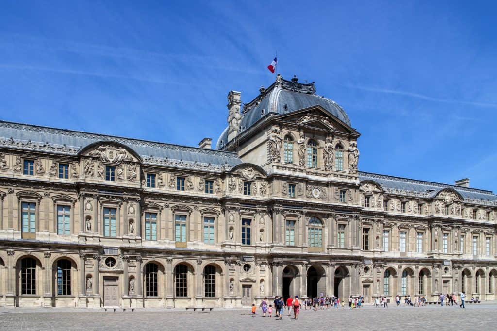 The ornate stone façades of the Palais du Louvre seen across the Cour Carrée.