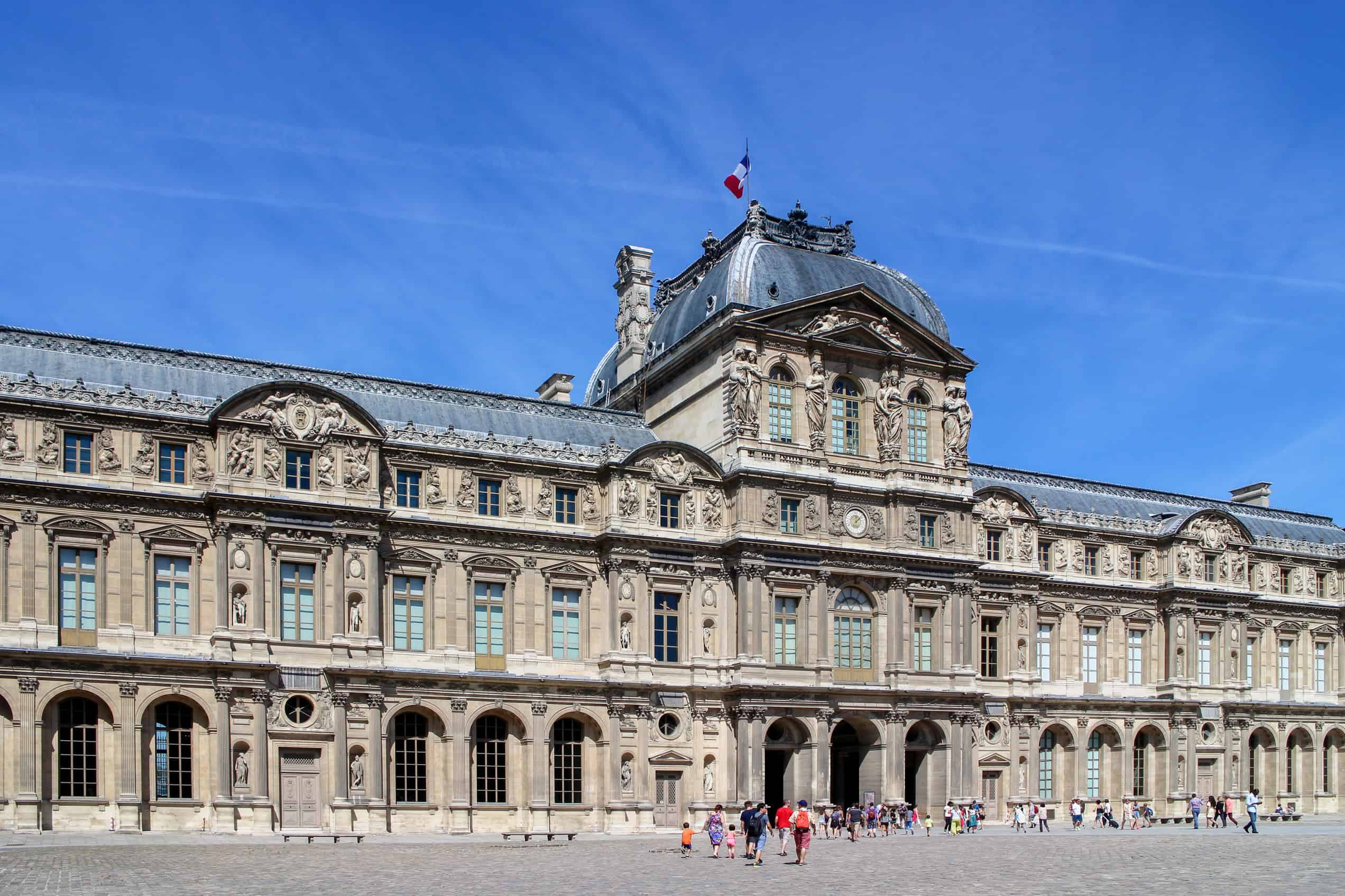 The ornate stone façades of the Palais du Louvre seen across the Cour Carrée.