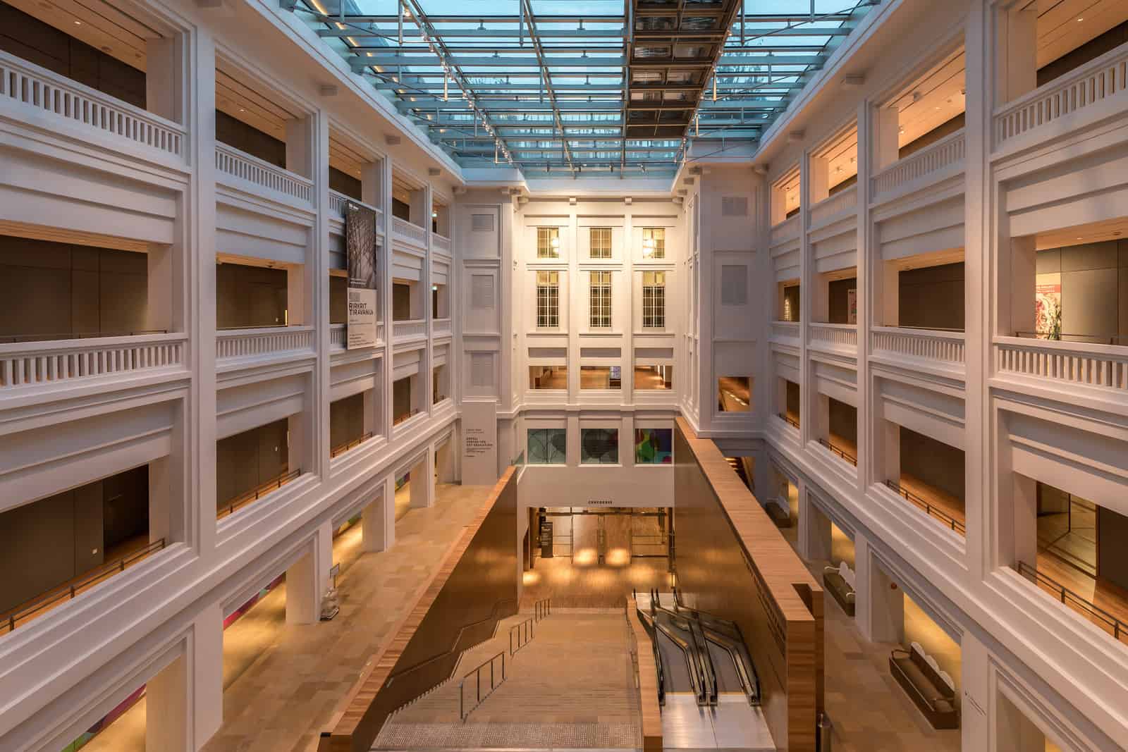 Multiple levels, corridors, stairs, and escalators inside National Gallery Singapore in the evening.