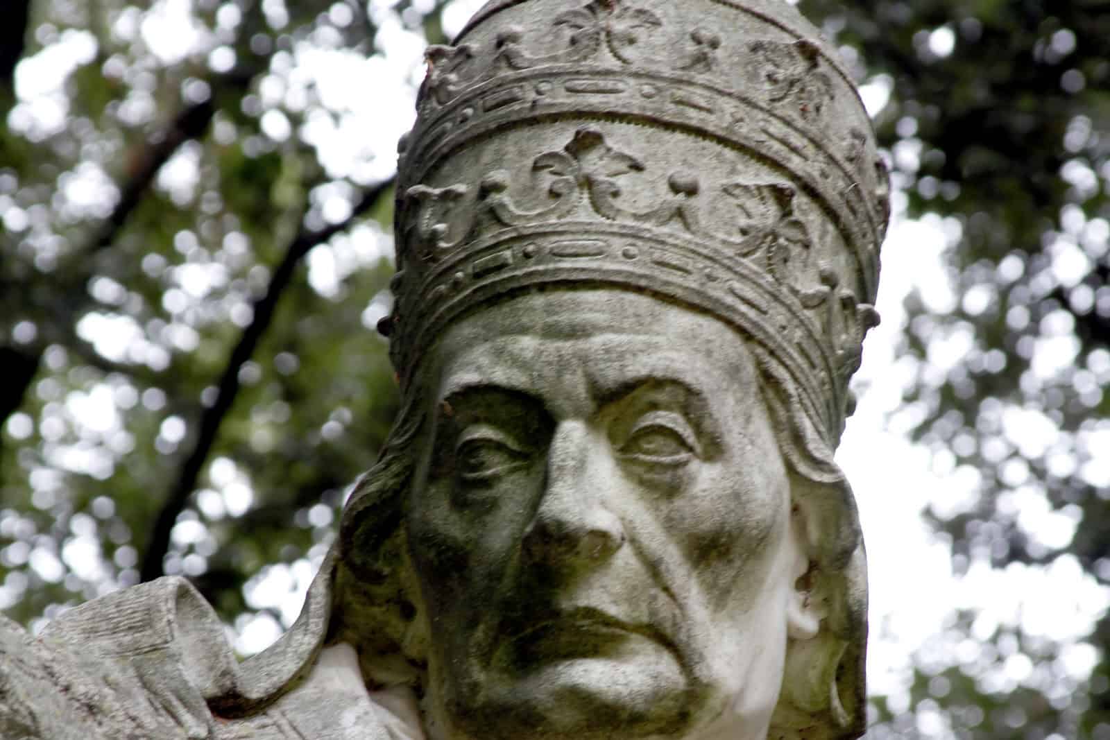 A close vertical view of the marble Pope Clement XII statue in the cloister of the National Museum of Ravenna.