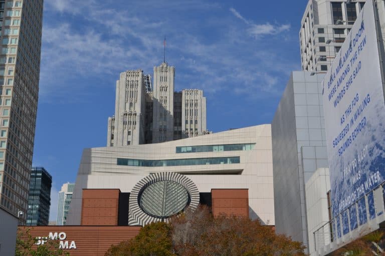 The San Francisco Museum of Modern Art building seen from the street beneath a blue sky.