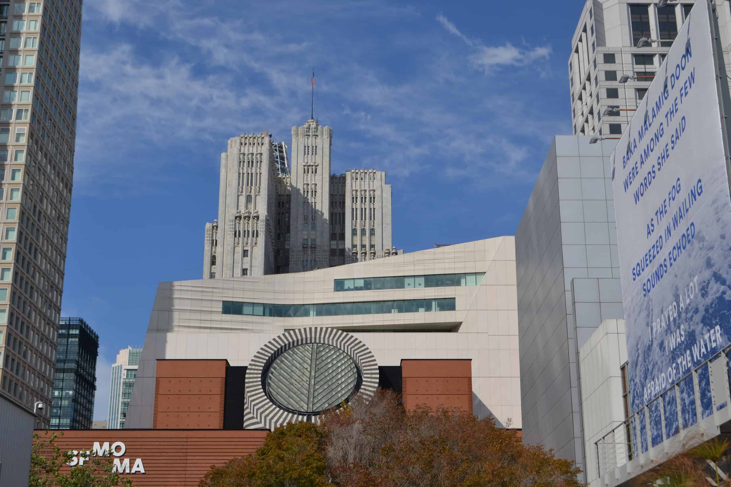 The San Francisco Museum of Modern Art building seen from the street beneath a blue sky.