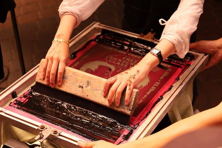 Screen printing: a squeegee pulls ink through the mesh screen
