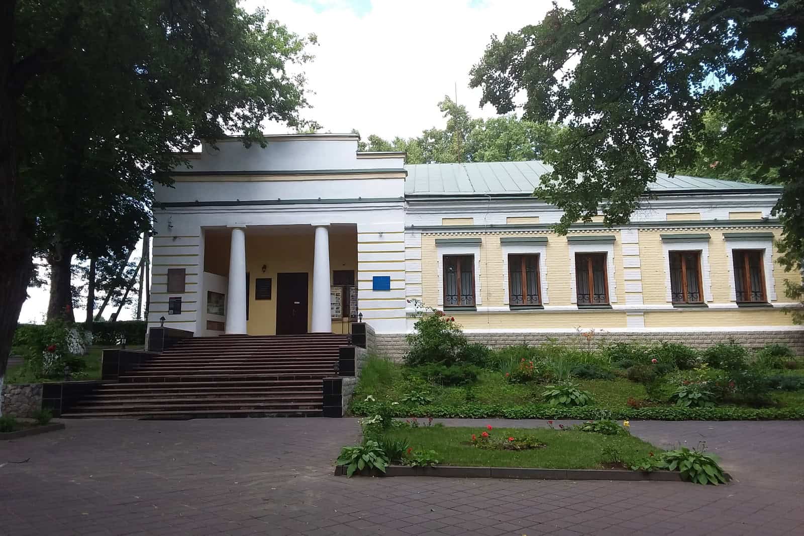 The yellow-and-white Hryhorii Skovoroda Museum stands among trees before the 2022 missile strike.