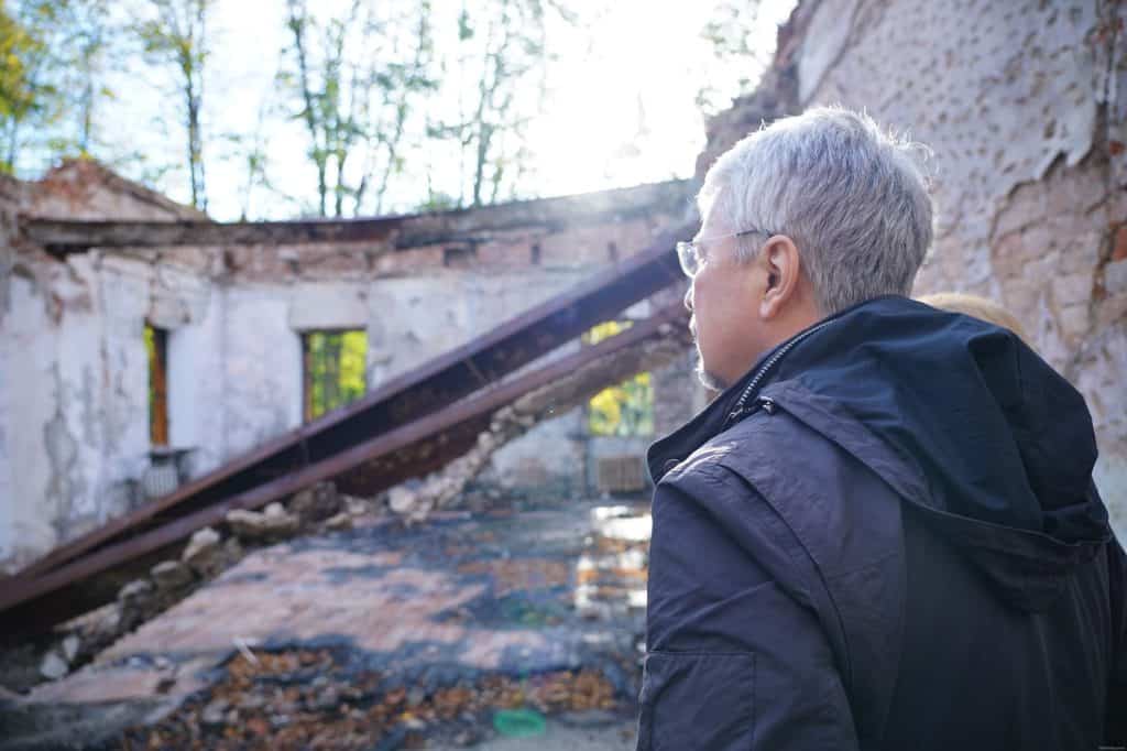 People stand beside the roofless, fire-damaged Hryhorii Skovoroda Museum in September 2022.