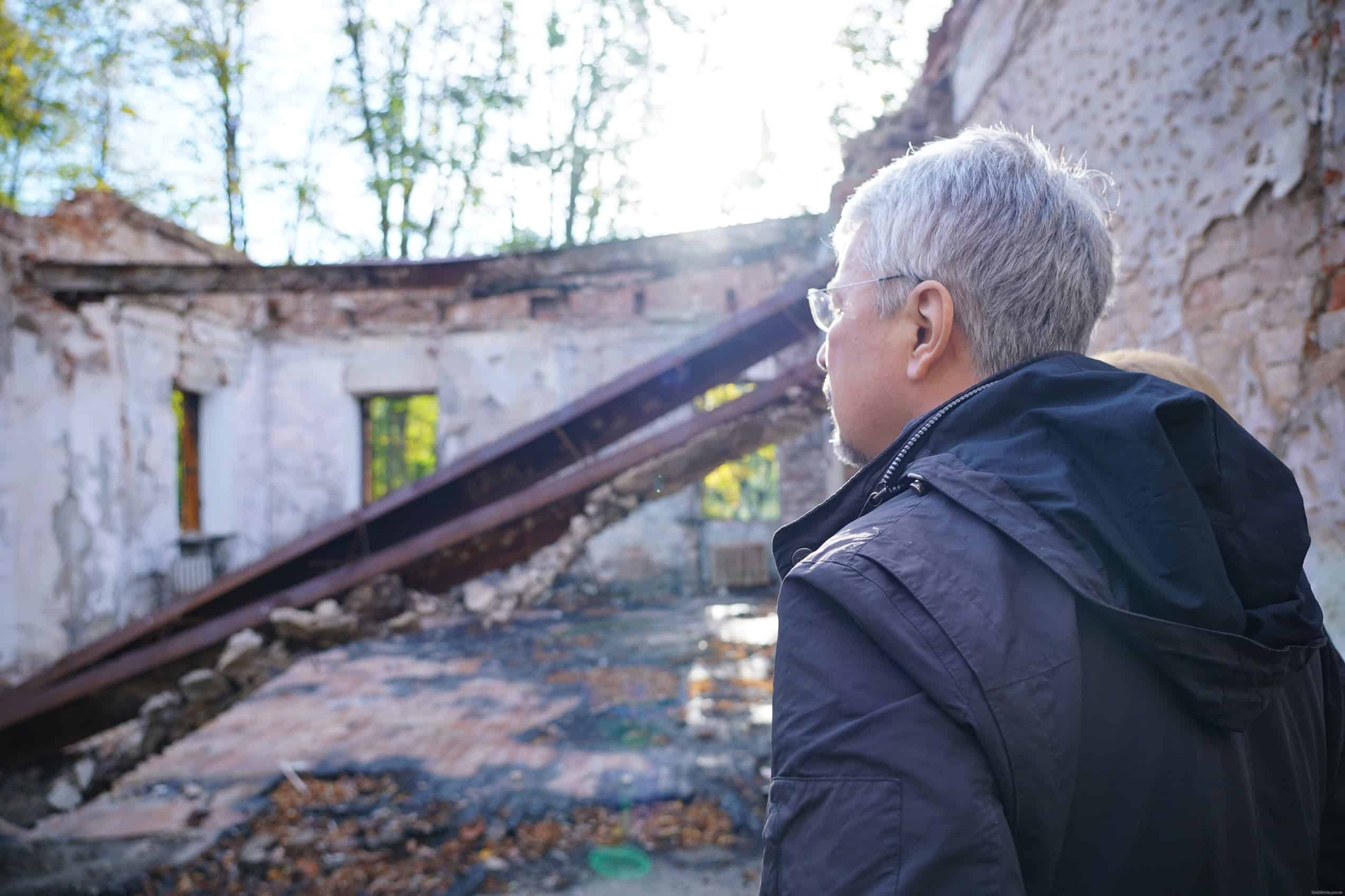 People stand beside the roofless, fire-damaged Hryhorii Skovoroda Museum in September 2022.