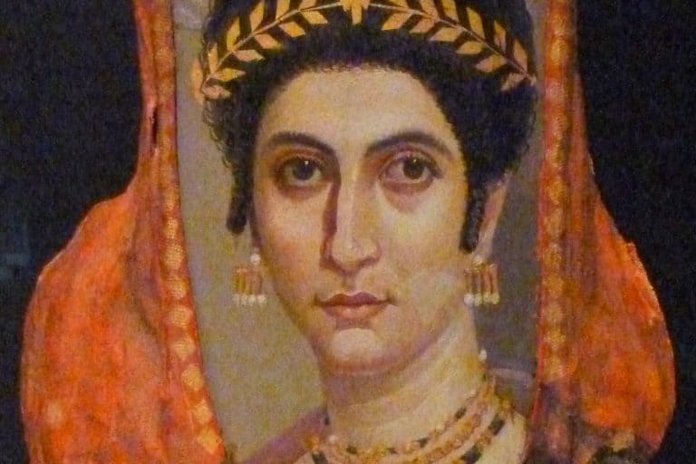 The mummy portrait of Isidora shows a dark-haired woman wearing a gold wreath and layered jewelry within red burial wrappings.